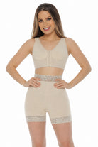 A woman modeling a beige two-piece shapewear set consisting of a bralette and high-waisted shorts with lace trim, against a plain white background.